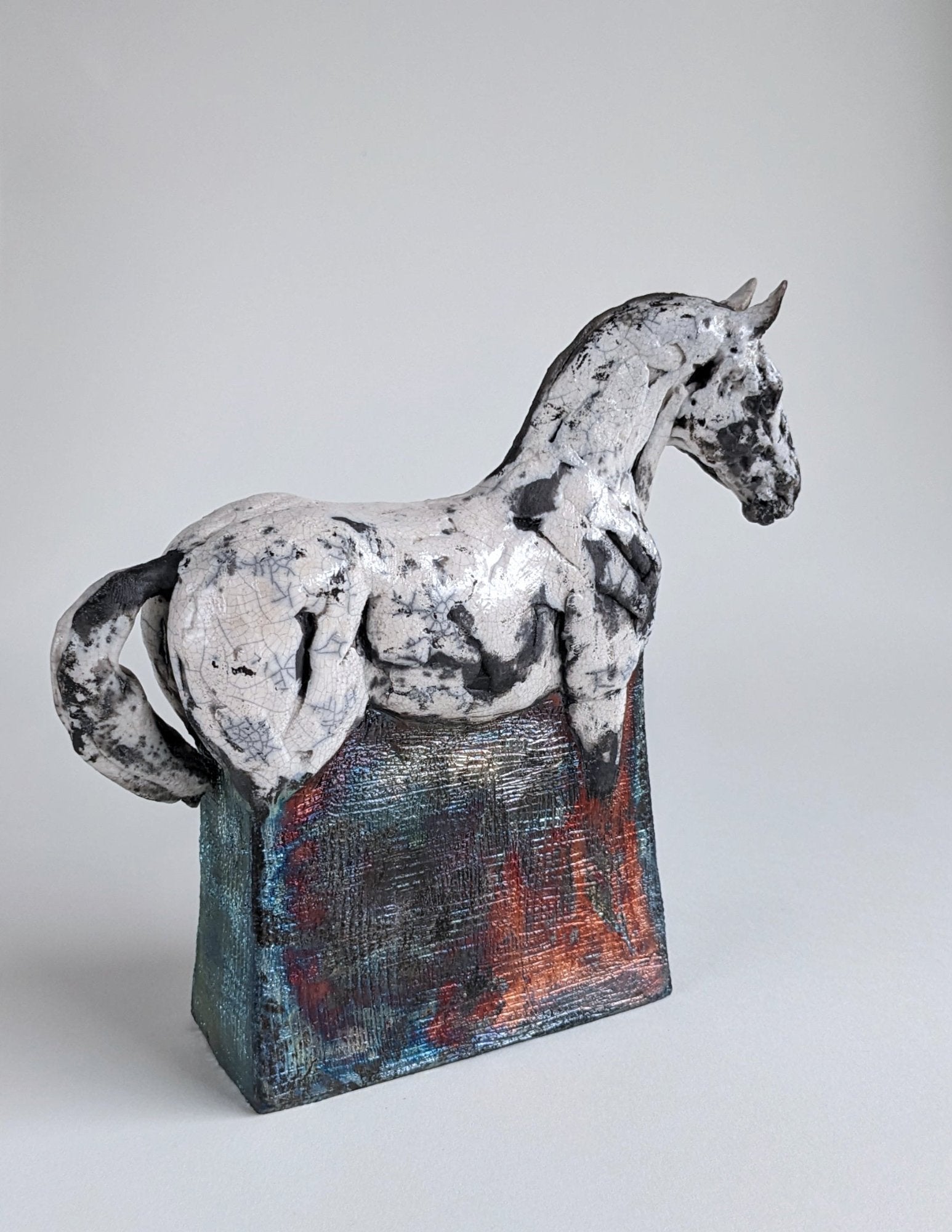 White and metallic ceramic horse sculpture in hand