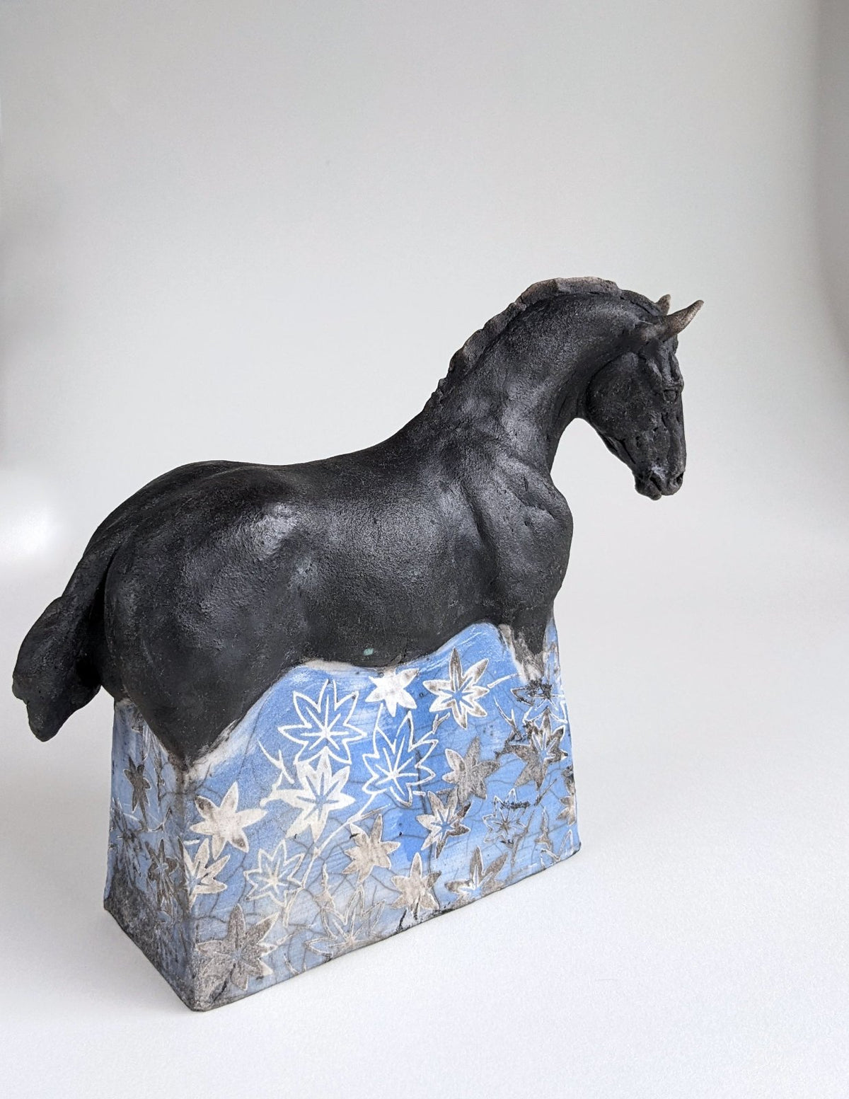 Black ceramic horse sculpture with blue and white flowers