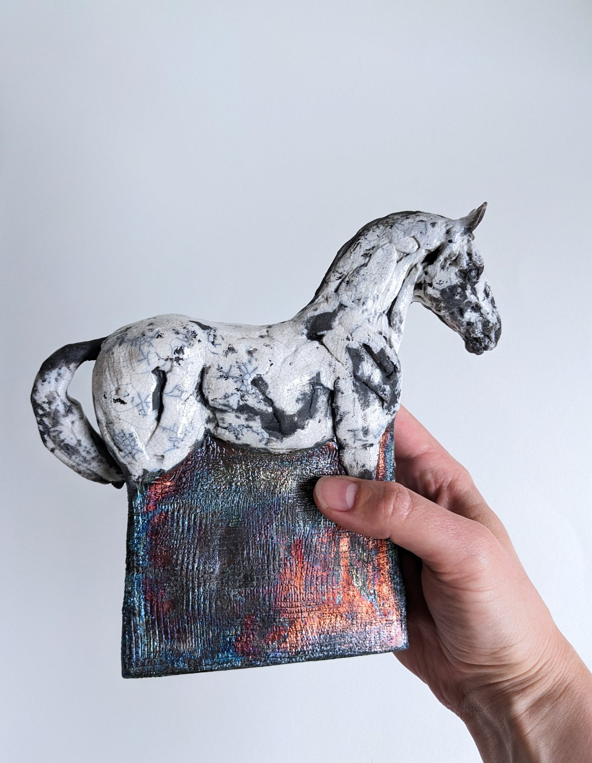 White and metallic ceramic horse sculpture in hand