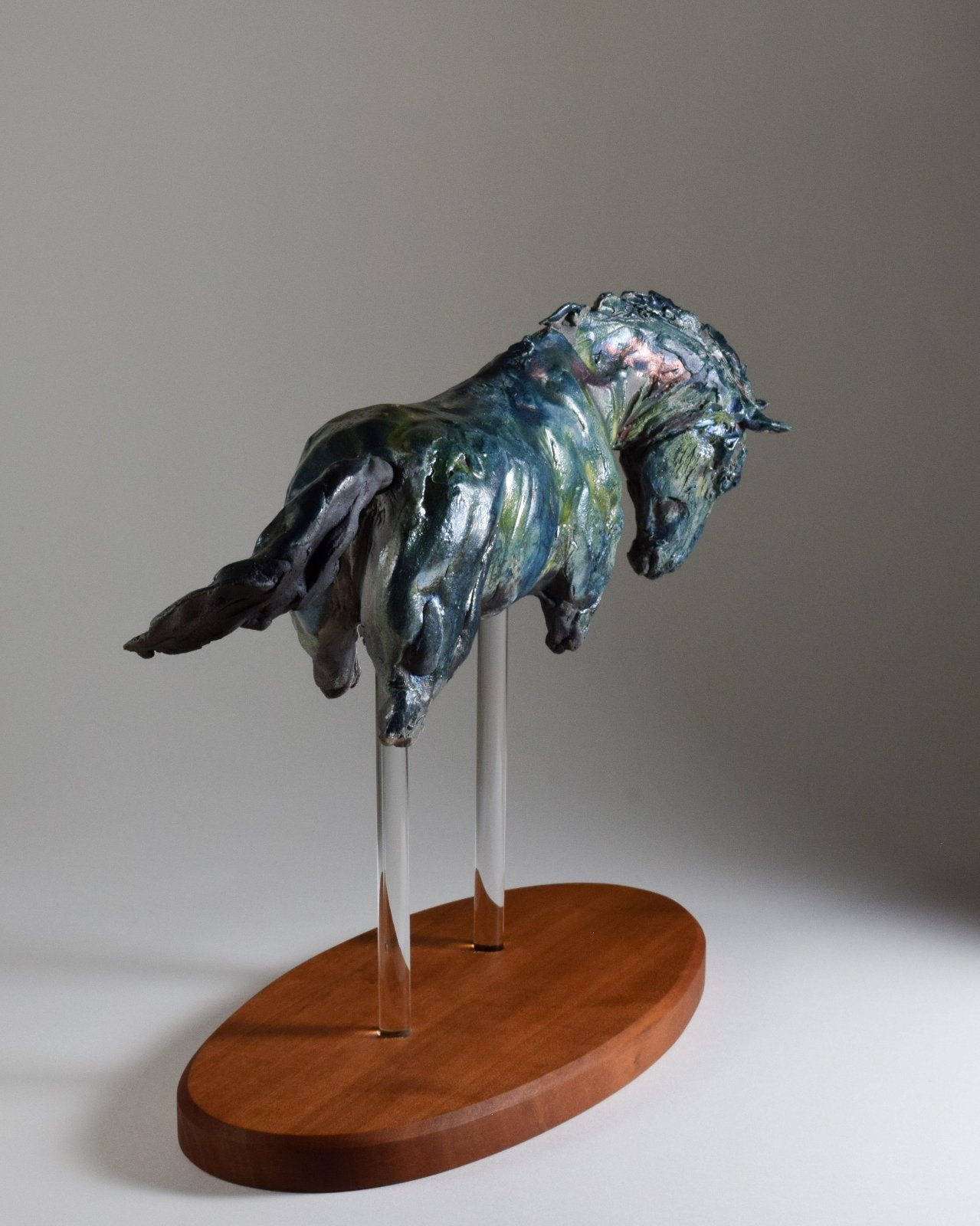 Cantering blue ceramic horse sculpture on wood base