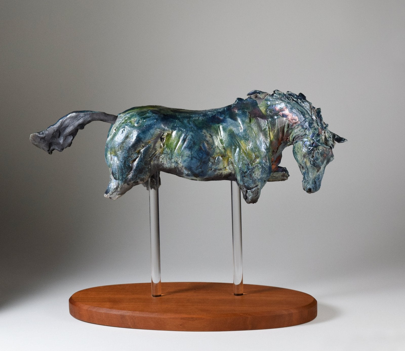 Cantering blue ceramic horse sculpture on wood base