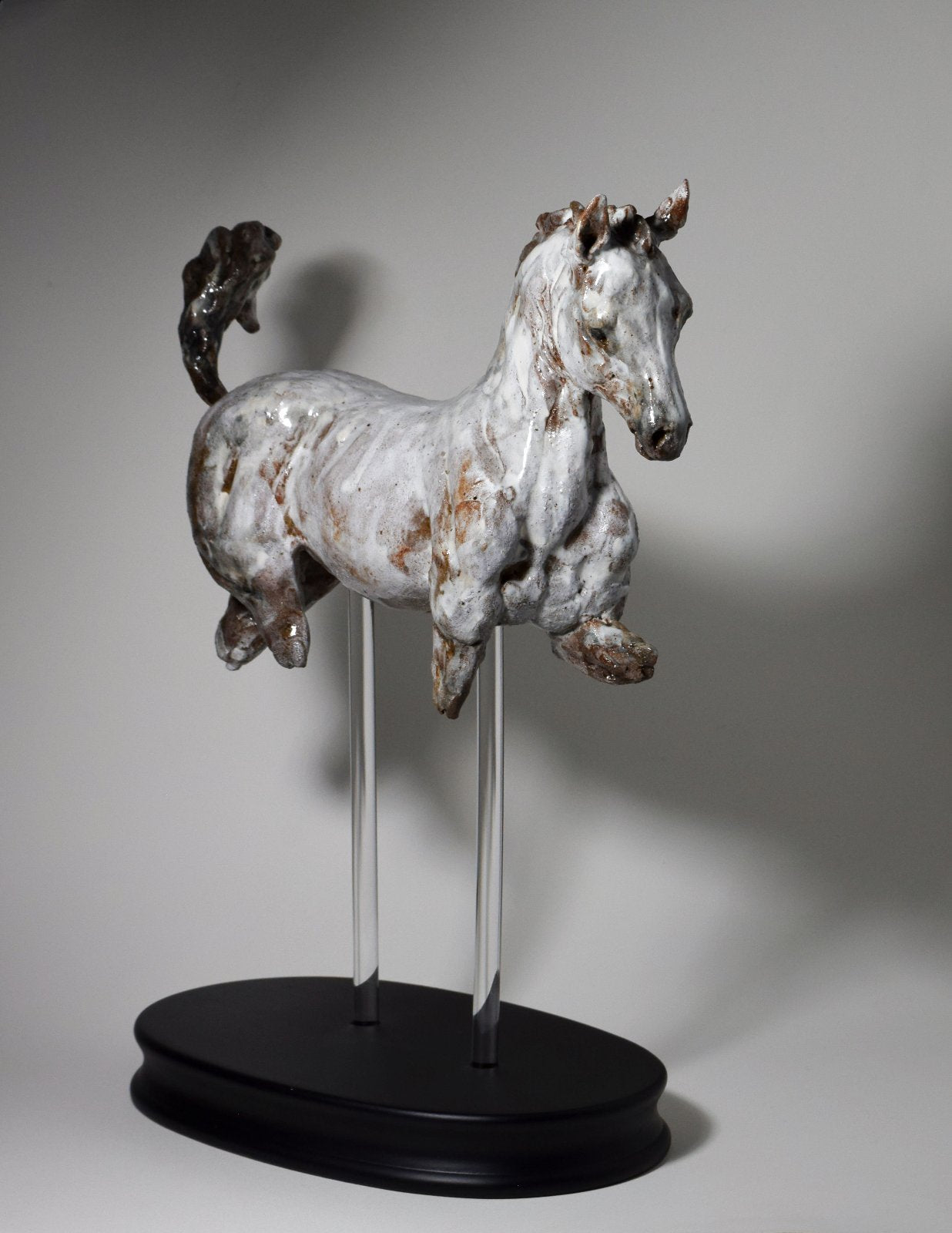 Grey white cantering ceramic horse sculpture on wood base by Susie Benes