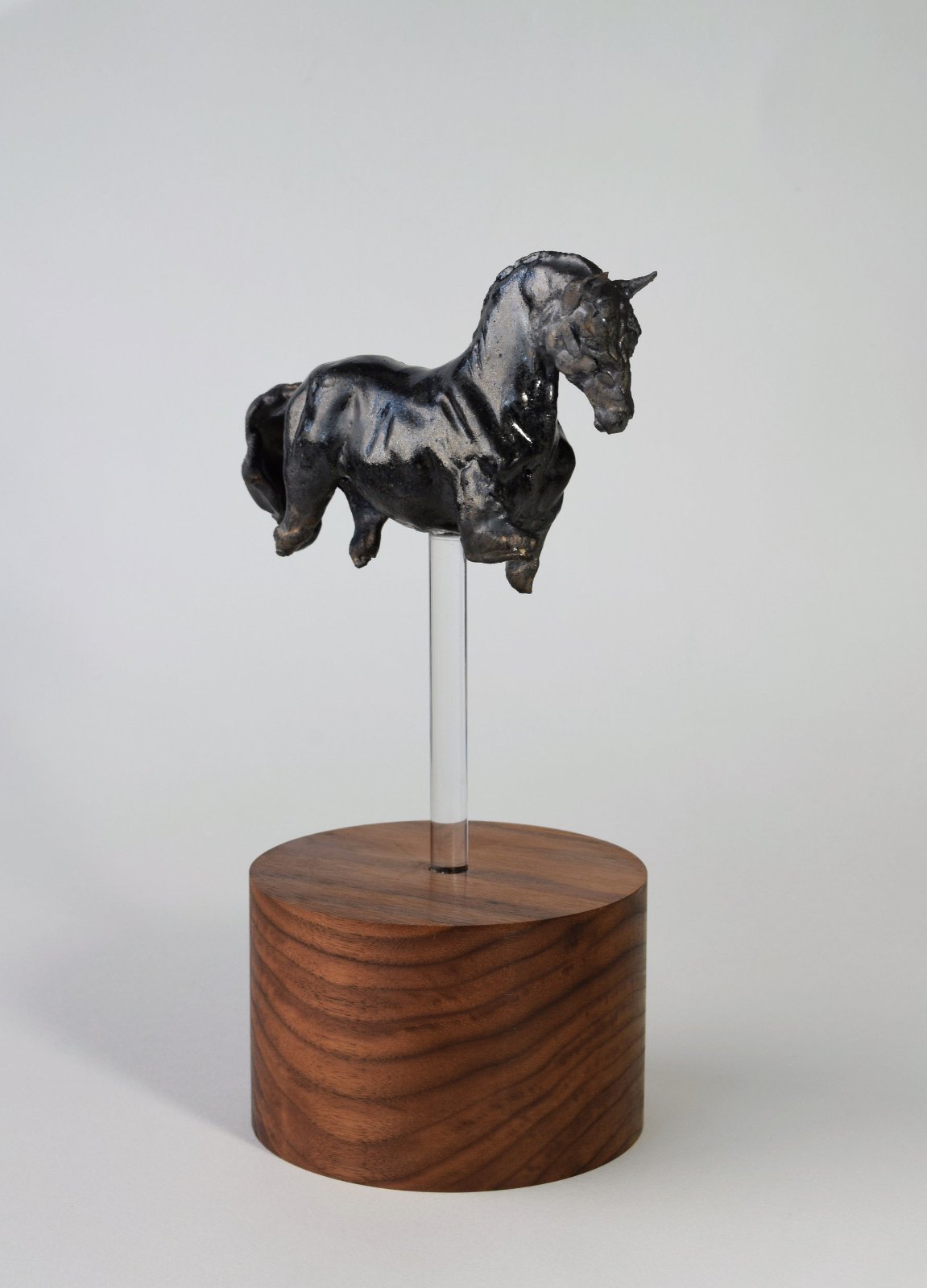 Black ceramic horse sculpture on tall wood base