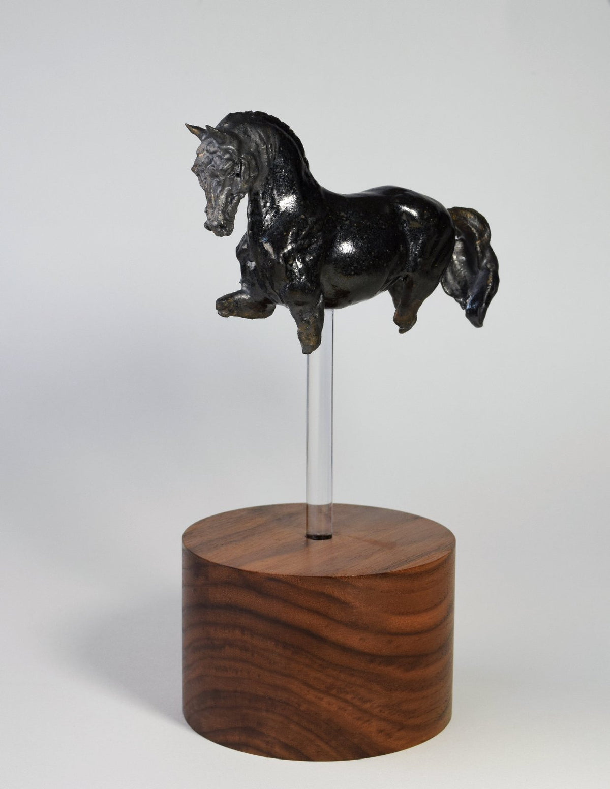 Black ceramic horse sculpture on tall wood base